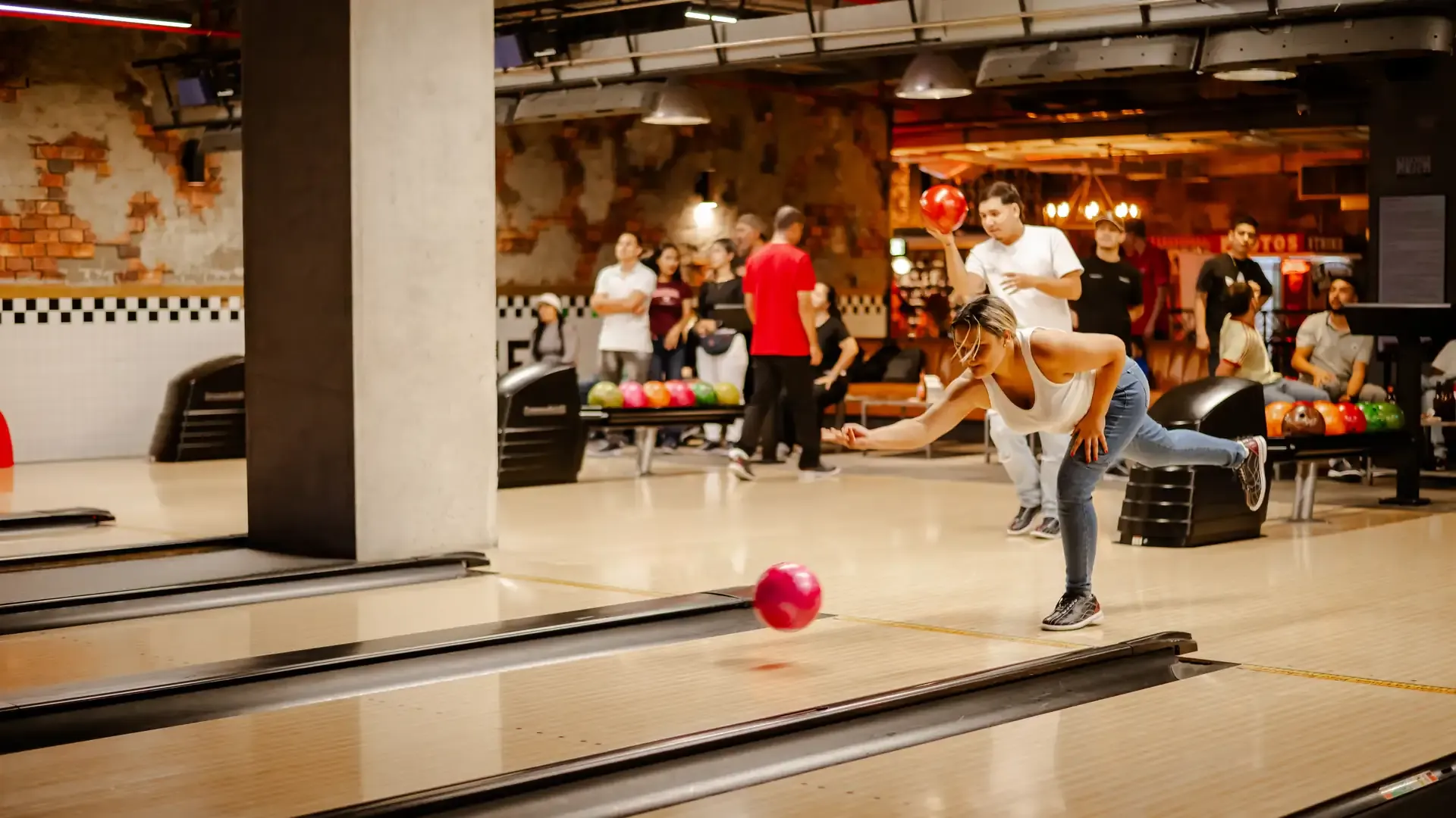 Una jugadora lanza la bola por una de las pistas de bolos